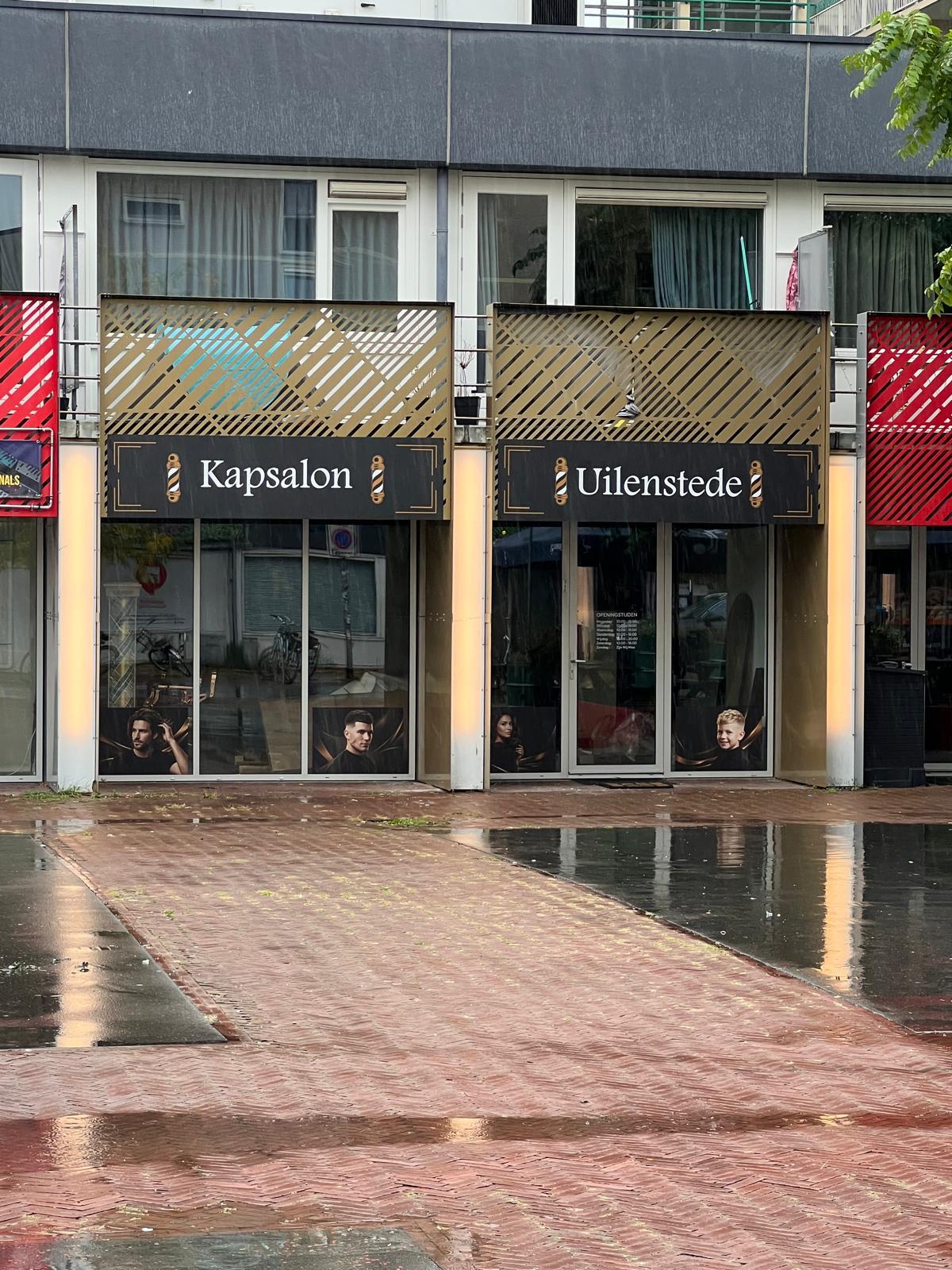 De gevel aan Uilenstede 352: twee zwarte borden met Kapsalon en Uilenstede, met barberpalen